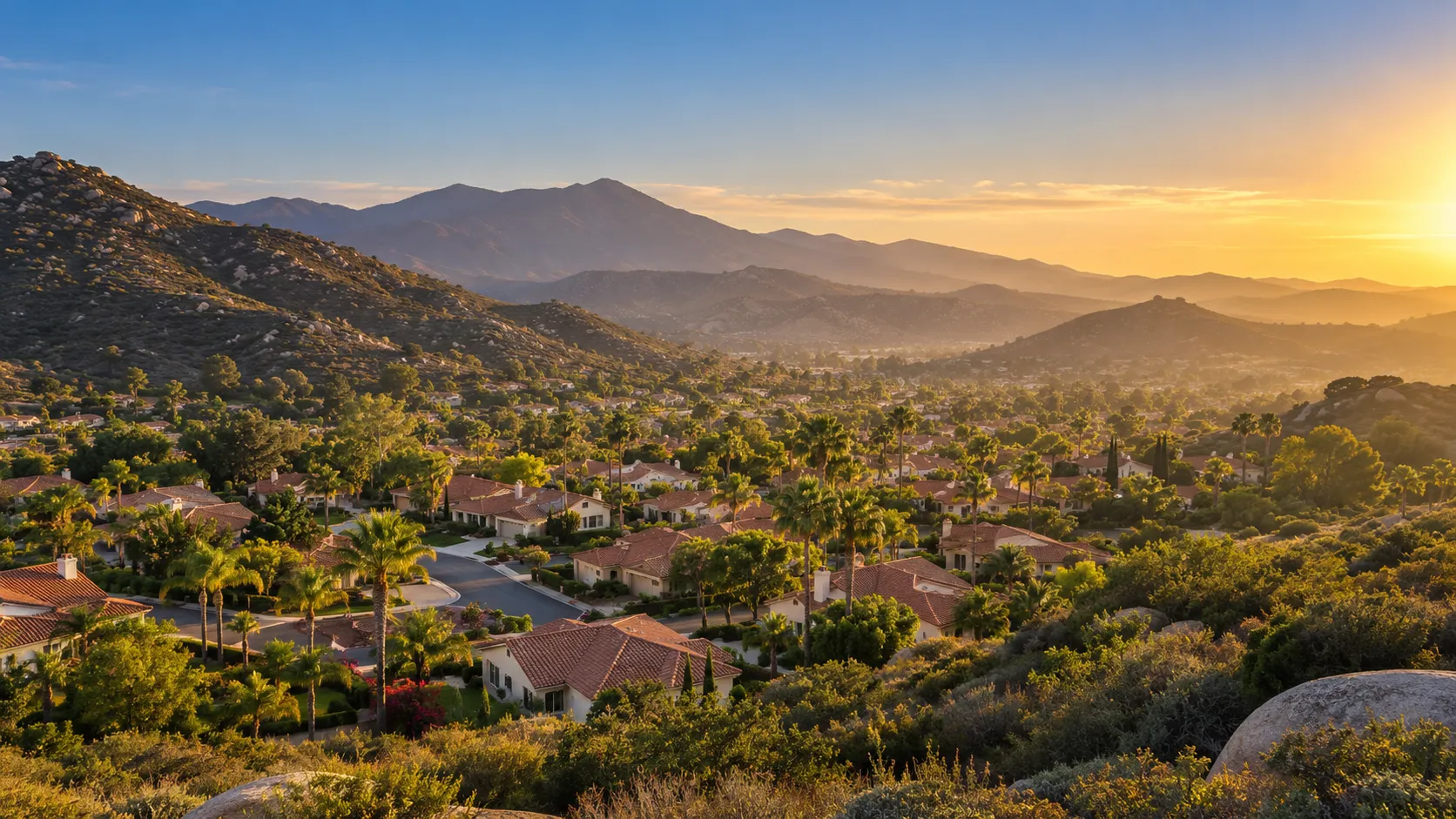 Homes in a San Diego County valley with hills behind at golden hour